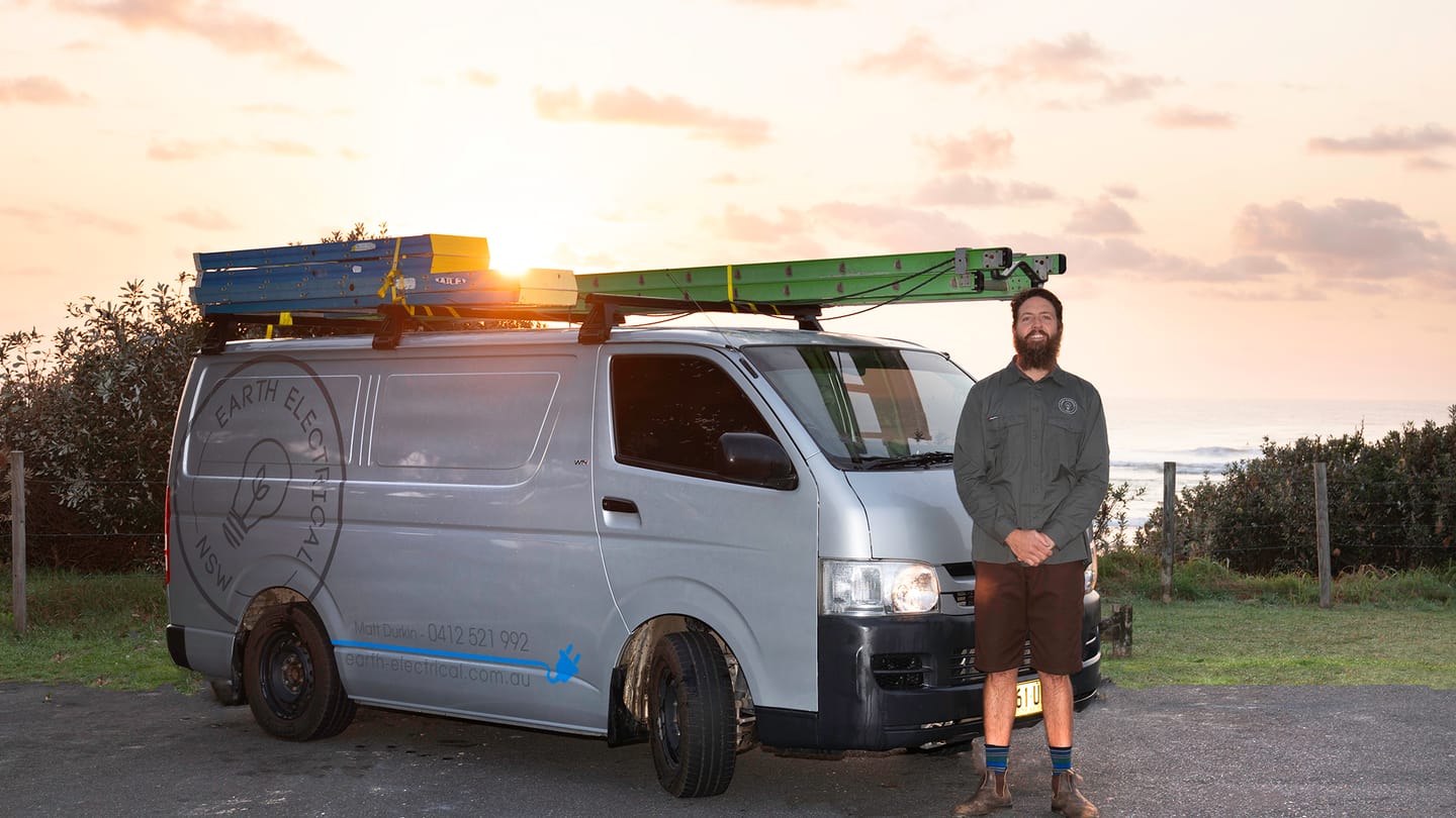 The Earth Electrical NSW van at Lennox Head at sunset, with Matt Durkin alongside it